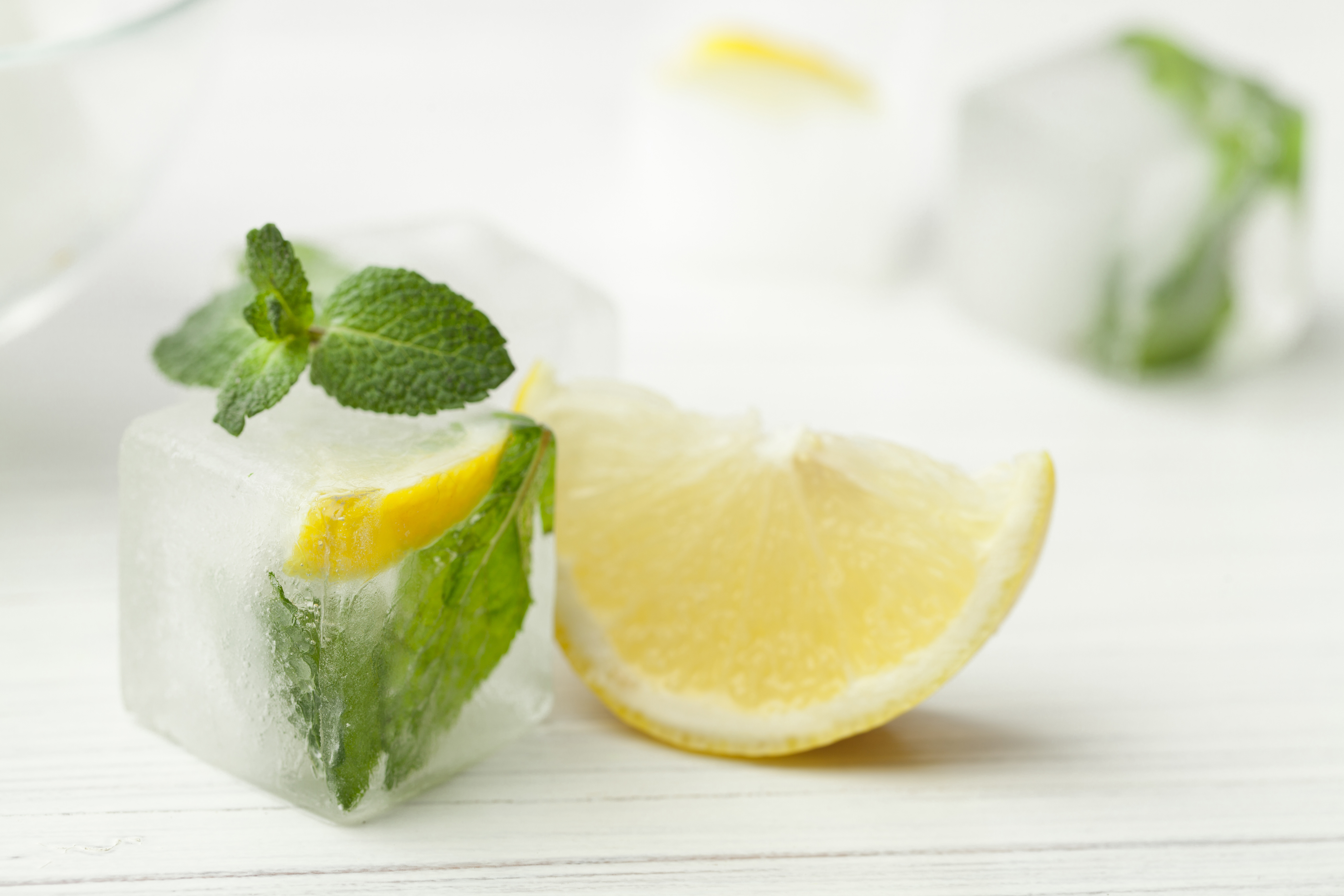 cosmetic ice with mint and lemon on white wooden table